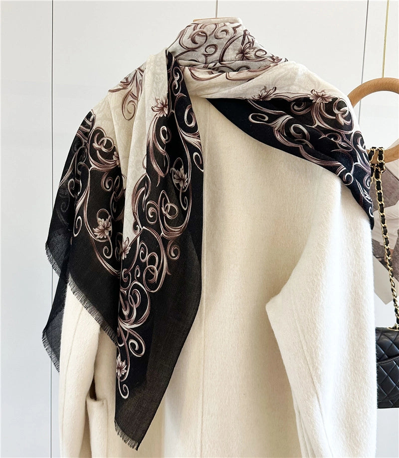 Black-bordered Baroque wool scarf arranged as a shoulder wrap over an ivory coat
