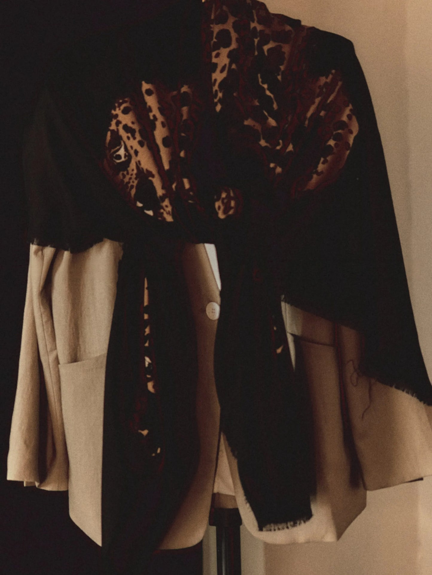 Black leopard print wool scarf styled as a shoulder wrap over a neutral layered outfit