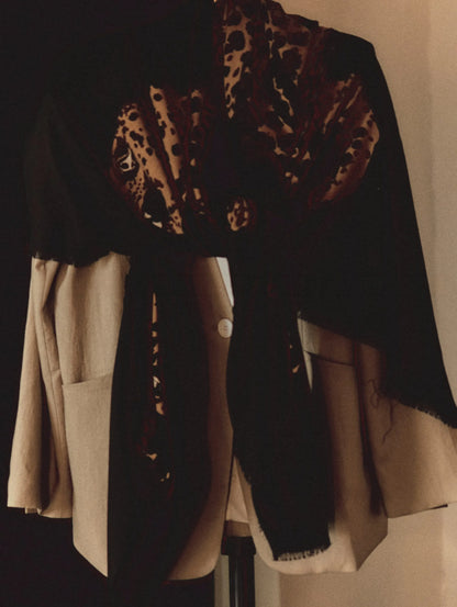 Black leopard print wool scarf styled as a shoulder wrap over a neutral layered outfit