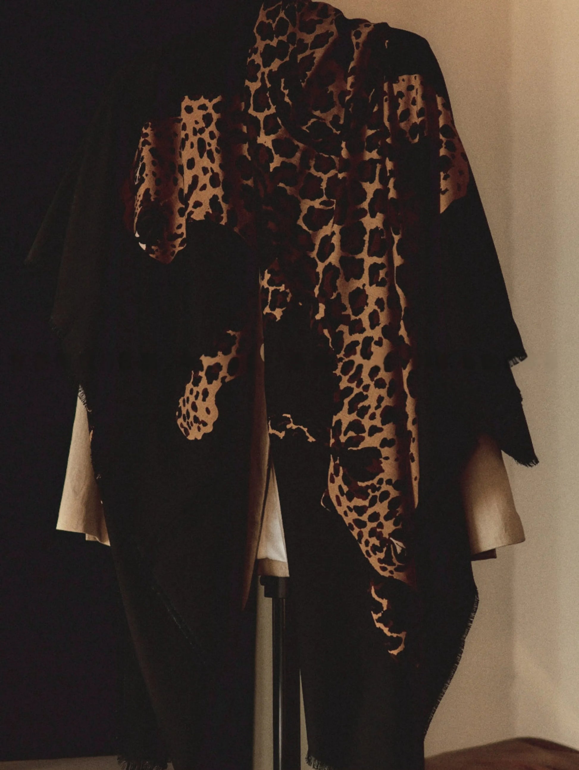 Oversized black leopard graphic wool shawl draped over the shoulders with an elegant monochrome outfit