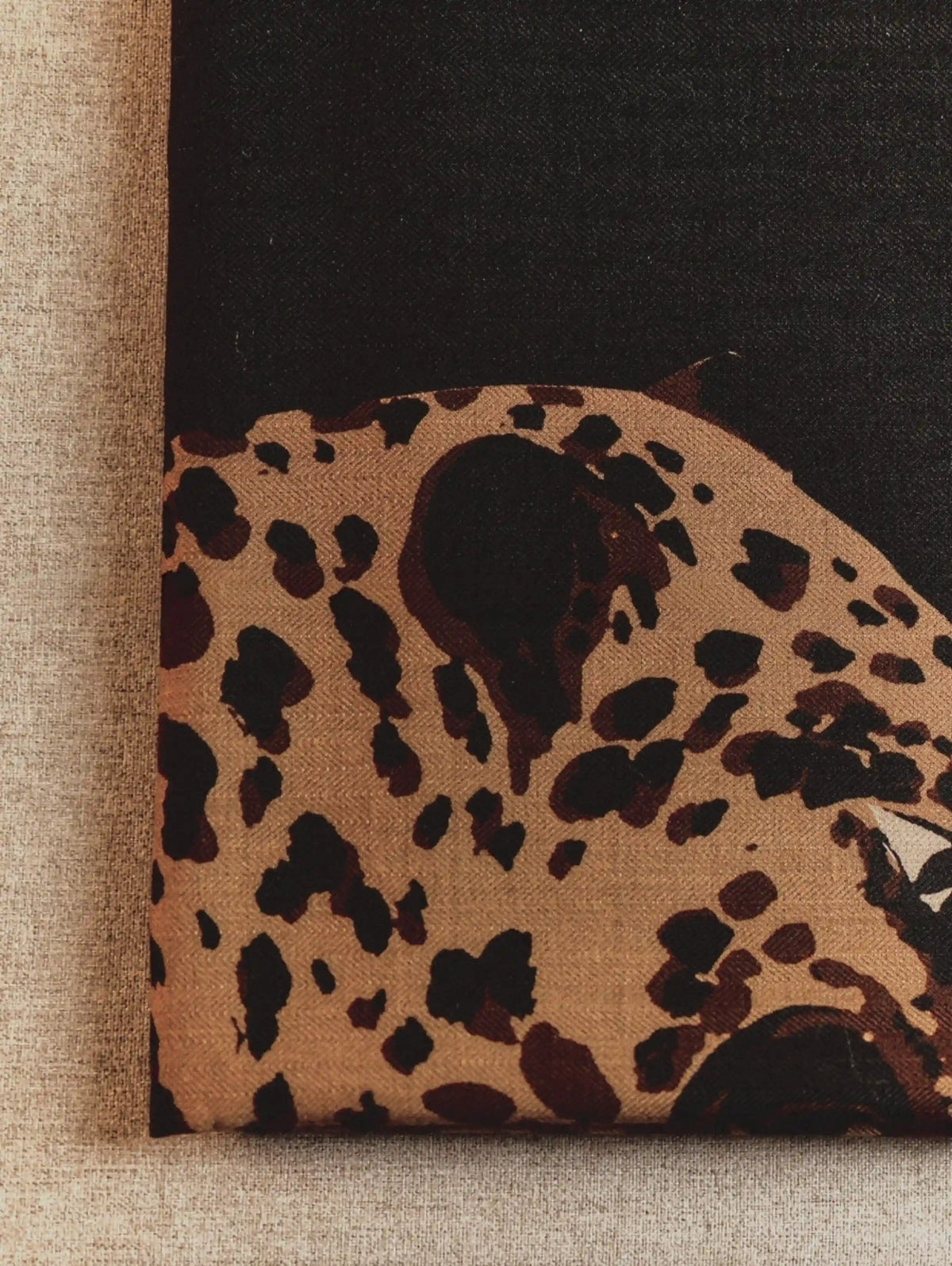 Close-up of the golden-brown leopard graphic on a black 100% wool scarf