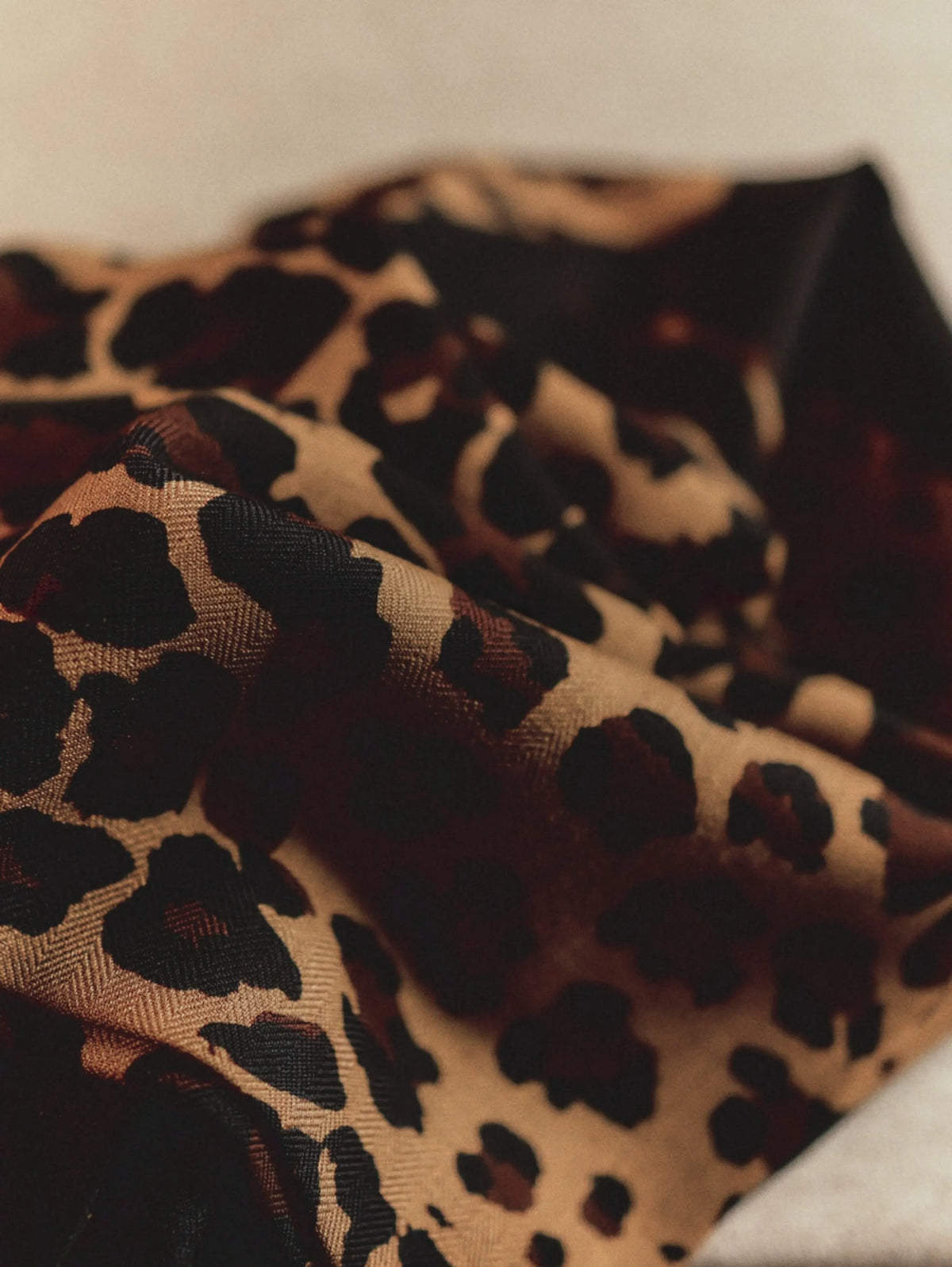 Close-up of the soft, lightweight black wool scarf with a golden-brown leopard print