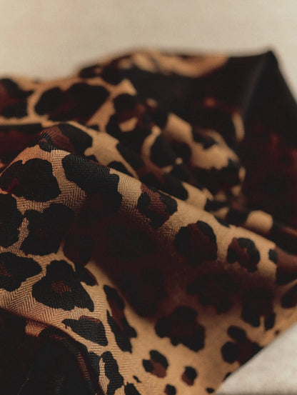 Close-up of the soft, lightweight black wool scarf with a golden-brown leopard print