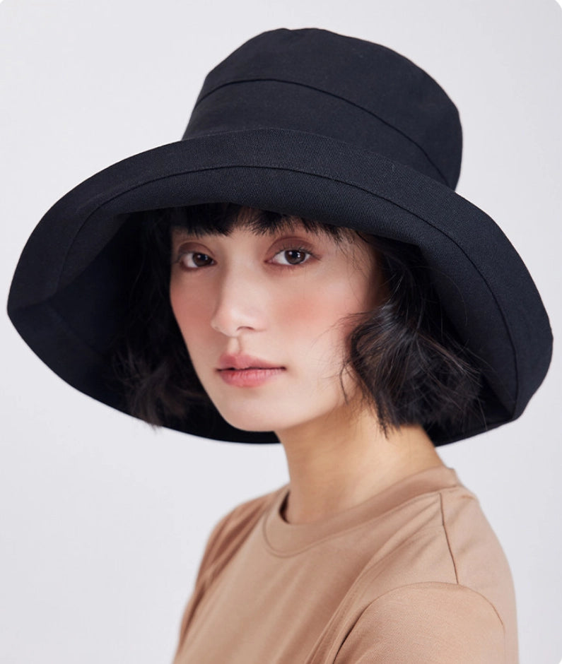 Woman wearing a black wide brim bucket sun hat for travel, beach, and outdoor summer wear