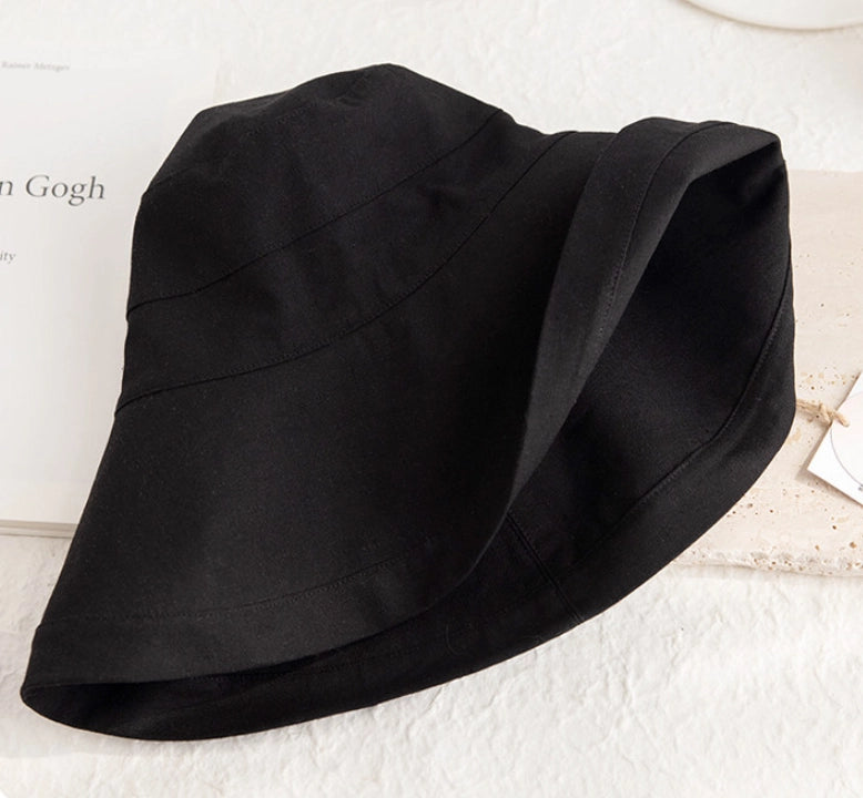 Close-up of a foldable black linen cotton sun hat showing its soft brim and fabric texture