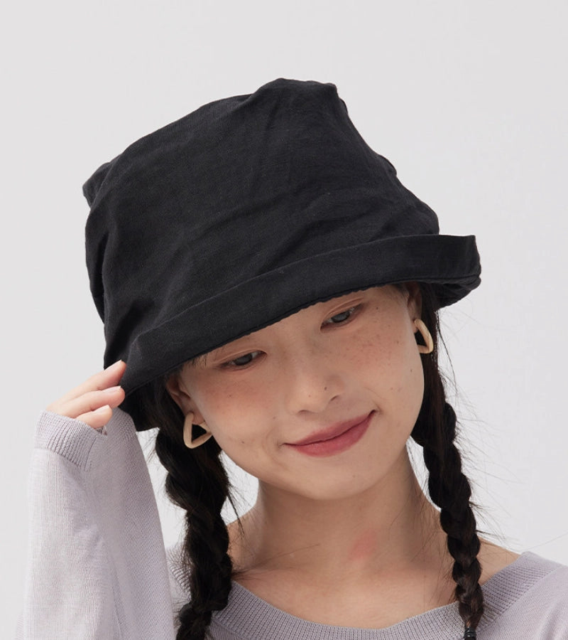 Woman wearing black crinkled linen bucket hat with relaxed rolled brim and minimalist summer style