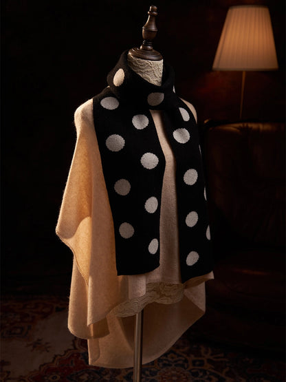 Angled view of a black polka dot cashmere scarf styled over a camel sweater on a mannequin.