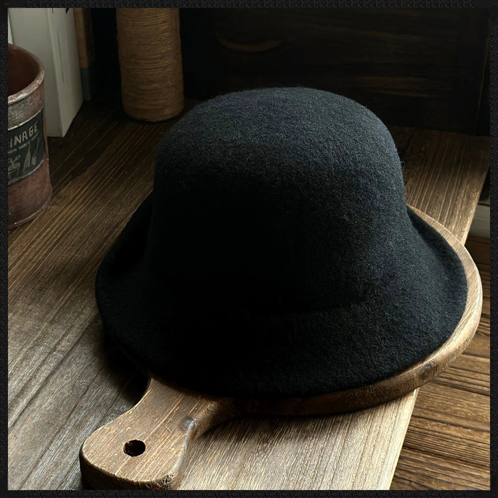 Rear view of a black wool felt cloche hat showing its smooth dome crown and rolled brim