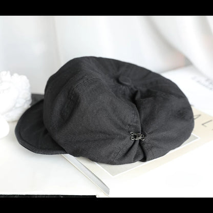 Black slouchy cotton beret hat with elastic adjustable fit, displayed on a book for casual everyday styling