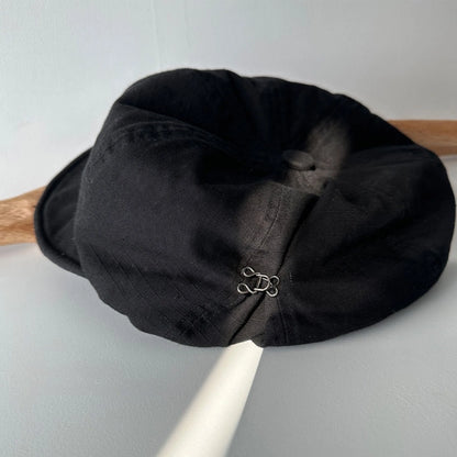 Black cotton beret hat side detail showing breathable fabric texture and adjustable elastic design