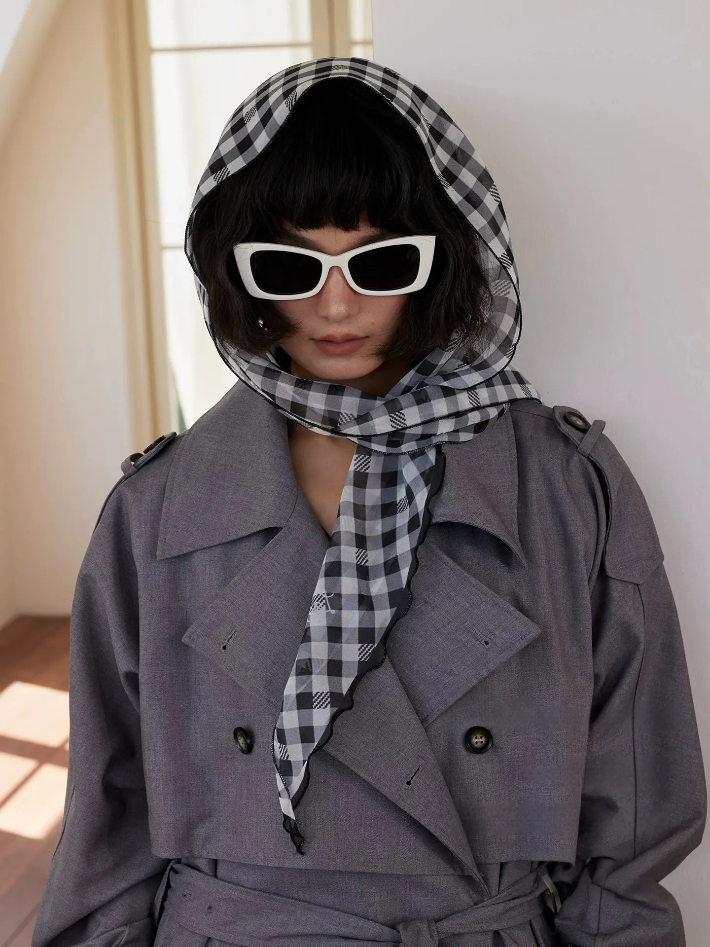 Black white gingham silk head scarf styled with trench coat and sunglasses for chic travel wear