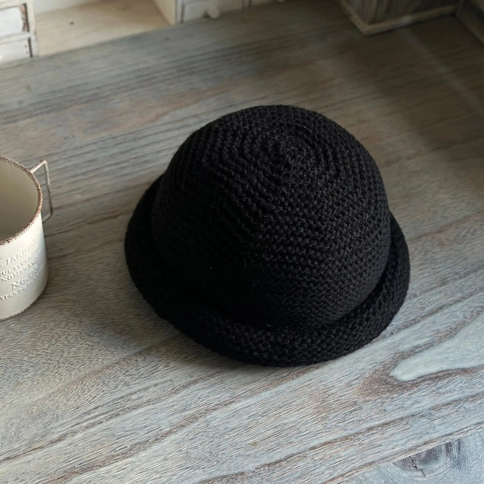 Top view of a black rolled brim knit beanie showing spiral crown stitching and a rounded shape