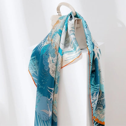 Large blue silk square scarf hanging with artistic animal kingdom pattern and refined silk drape.