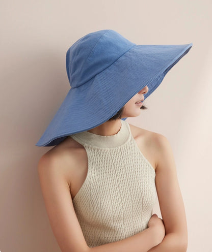 Woman styling blue oversized cotton sun hat with wide brim and soft breathable fabric