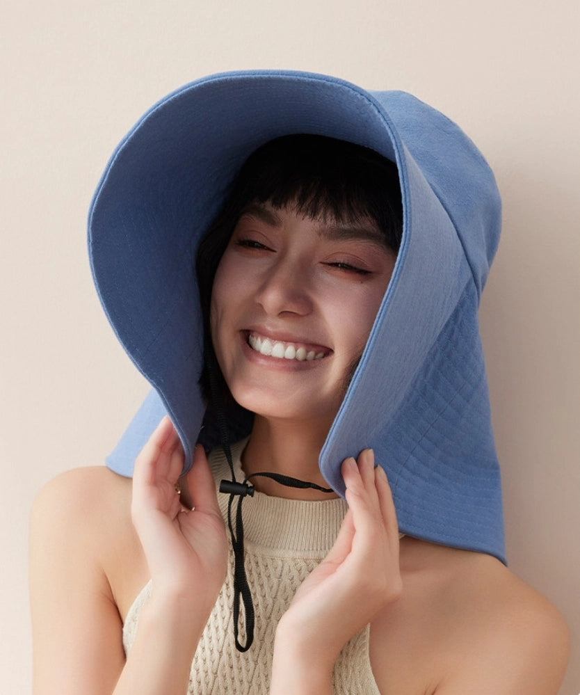 Smiling woman wearing blue wide brim summer hat with adjustable wind cord for beach and travel