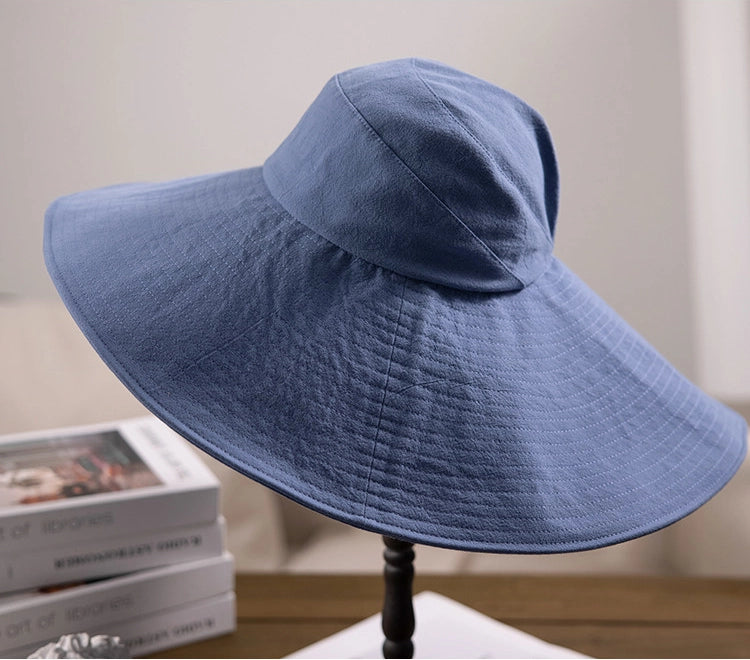 Blue cotton oversized wide brim sun hat displayed on table with soft foldable brim and wind cord