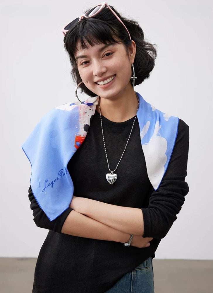 Fashion model wearing blue dalmatian print silk square scarf as an elegant shoulder accessory