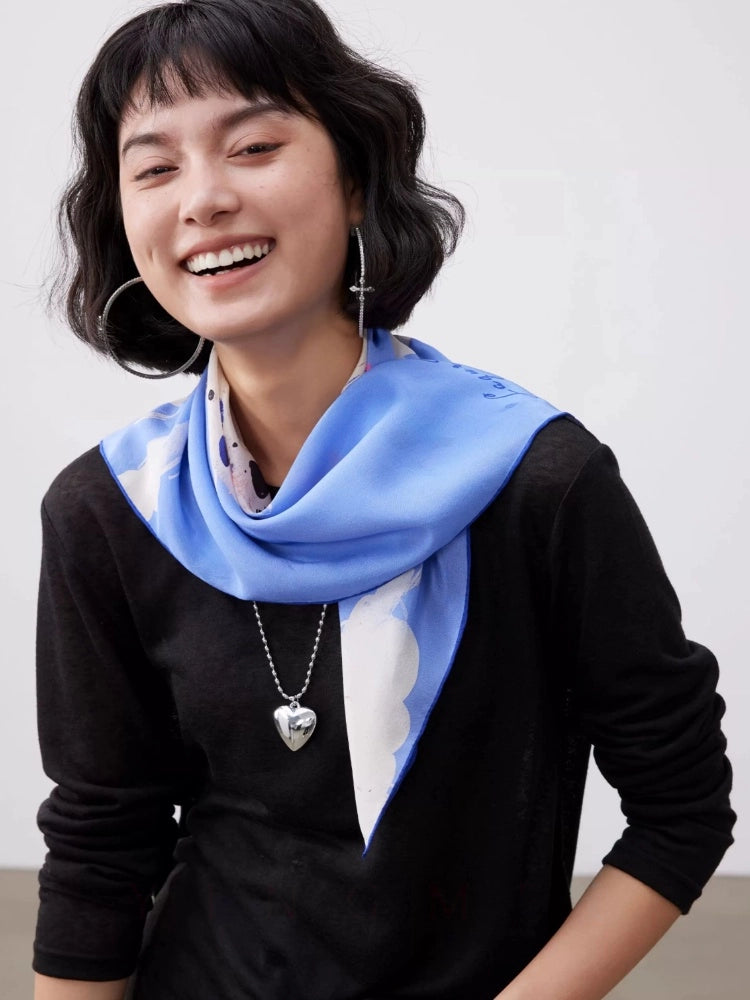 Elegant blue 100% mulberry silk square scarf styled around the neck with playful dalmatian print