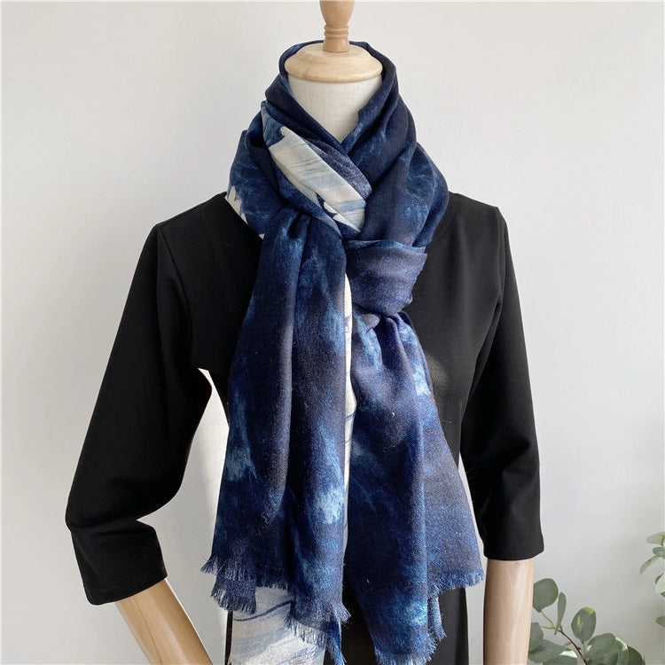 Blue galaxy wool scarf styled in a long knotted drape over a black dress on a mannequin