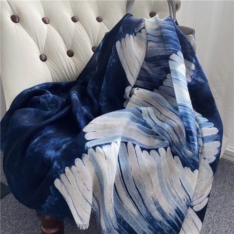 Oversized galaxy ocean wool wrap arranged on a tufted chair with flowing ivory wave motifs