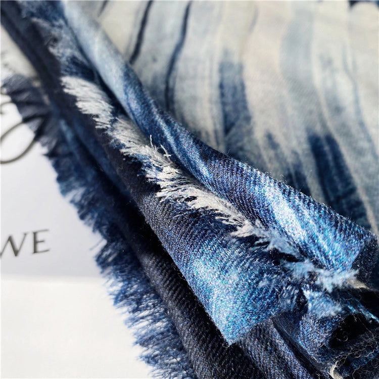 Close-up of the soft wool weave and fine fringed edge on a blue galaxy printed scarf