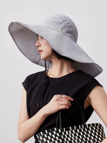 Blue gray UPF 100 wide brim sun hat styled with black dress for elegant outdoor sun protection