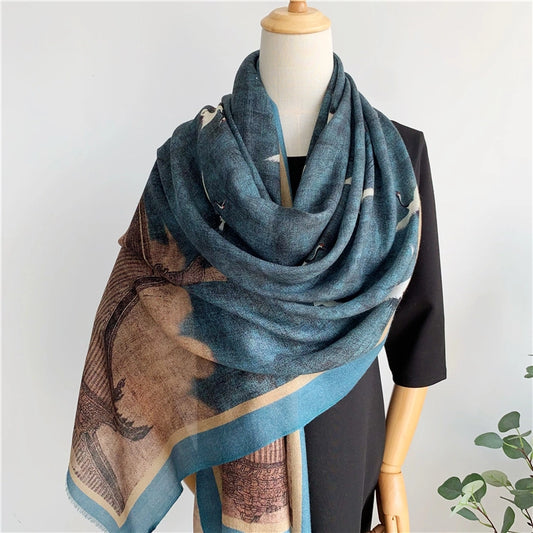 Mannequin wearing the blue crane and pavilion wool scarf as a voluminous shoulder wrap