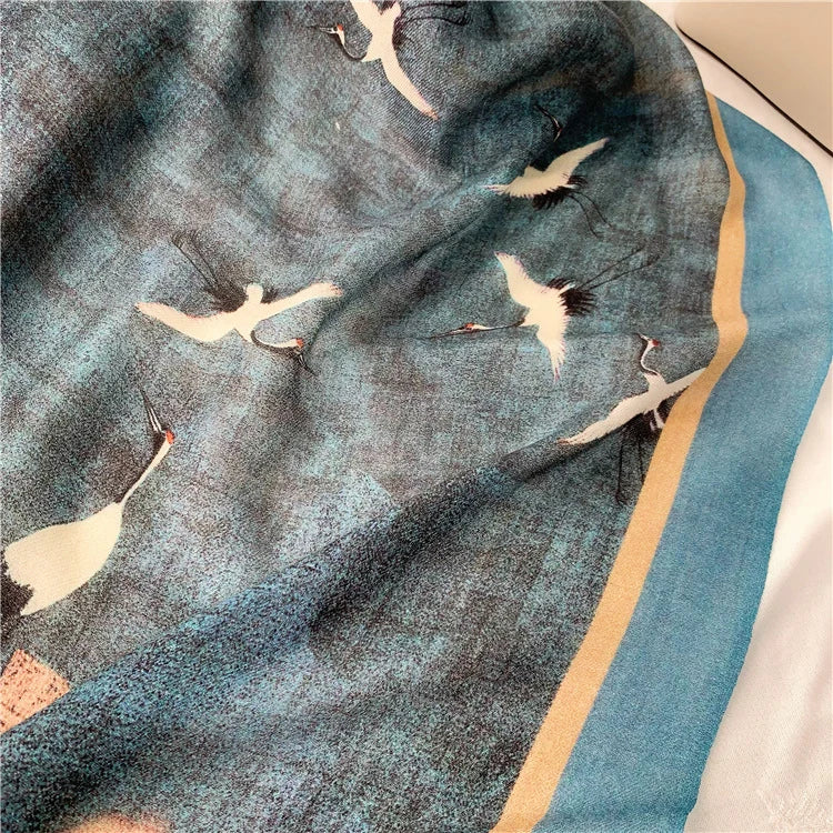 Blue fine wool scarf detail with flying white cranes and a turquoise border
