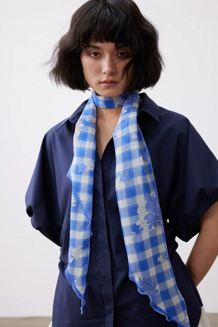 Blue white plaid mulberry silk skinny scarf styled loosely around the neck for an elegant everyday look.