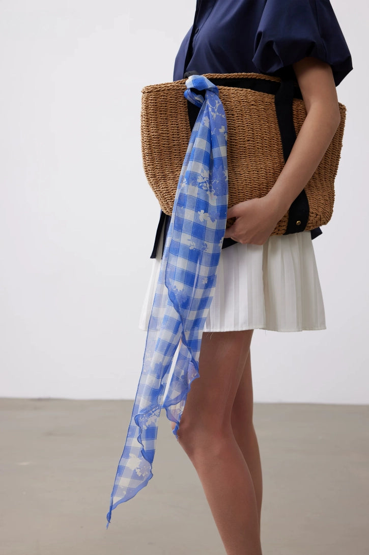 Long blue white plaid silk scarf styled with a woven bag for a fresh vacation and daily outfit accent.