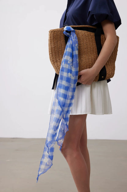 Long blue white plaid silk scarf styled with a woven bag for a fresh vacation and daily outfit accent.