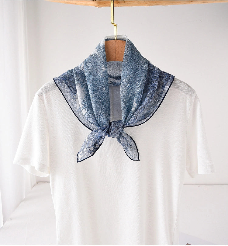 Blue botanical silk square scarf tied at the neck with a refined feminine look