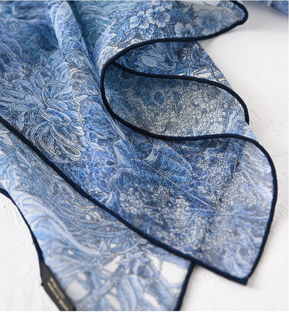 Close-up of blue botanical mulberry silk scarf showing delicate chiffon weave and rolled edge