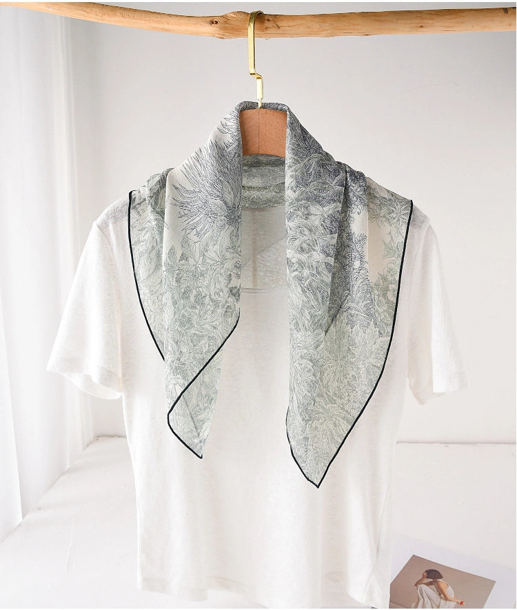 Deep green botanical mulberry silk neck scarf draped over a white top
