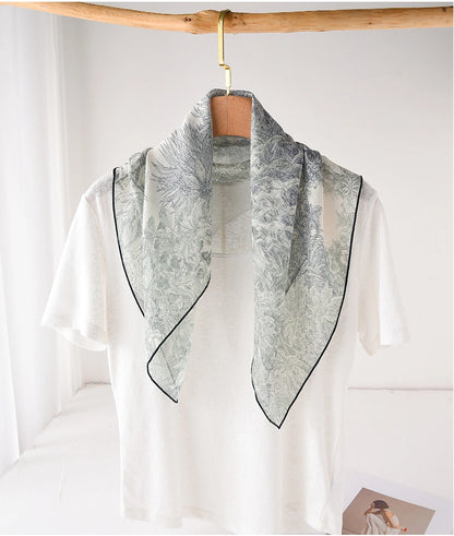 Deep green botanical mulberry silk neck scarf draped over a white top