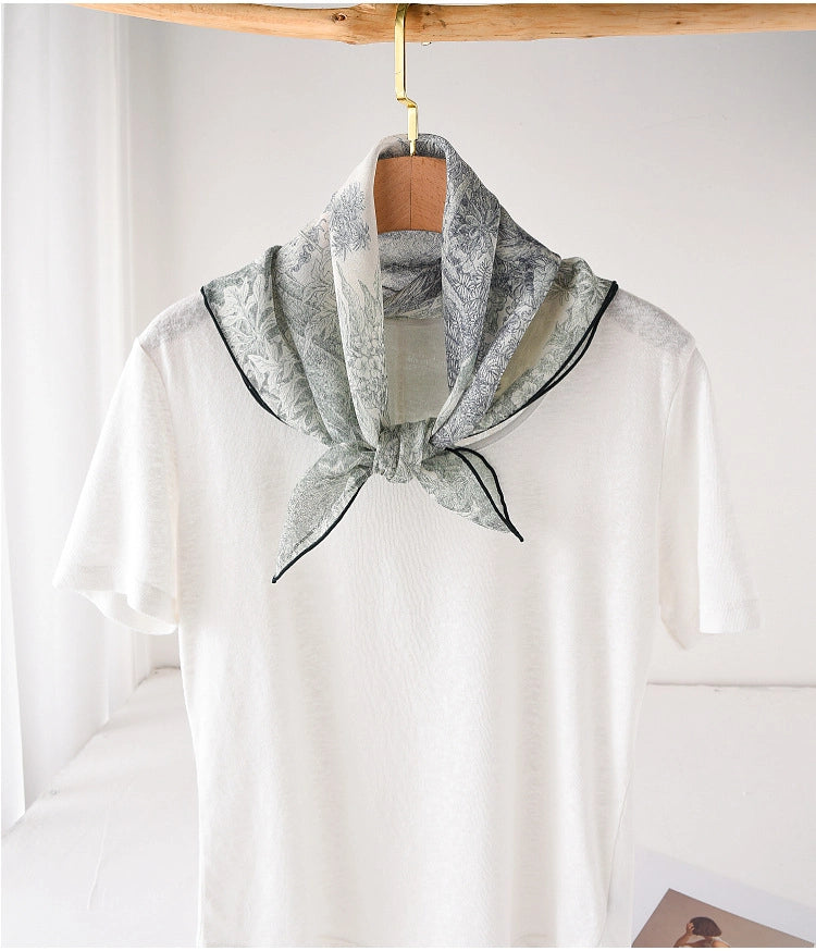 Deep green silk square scarf tied at the neck with elegant botanical print