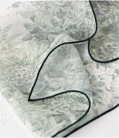 Close-up of deep green mulberry silk scarf with botanical pattern and delicate edging