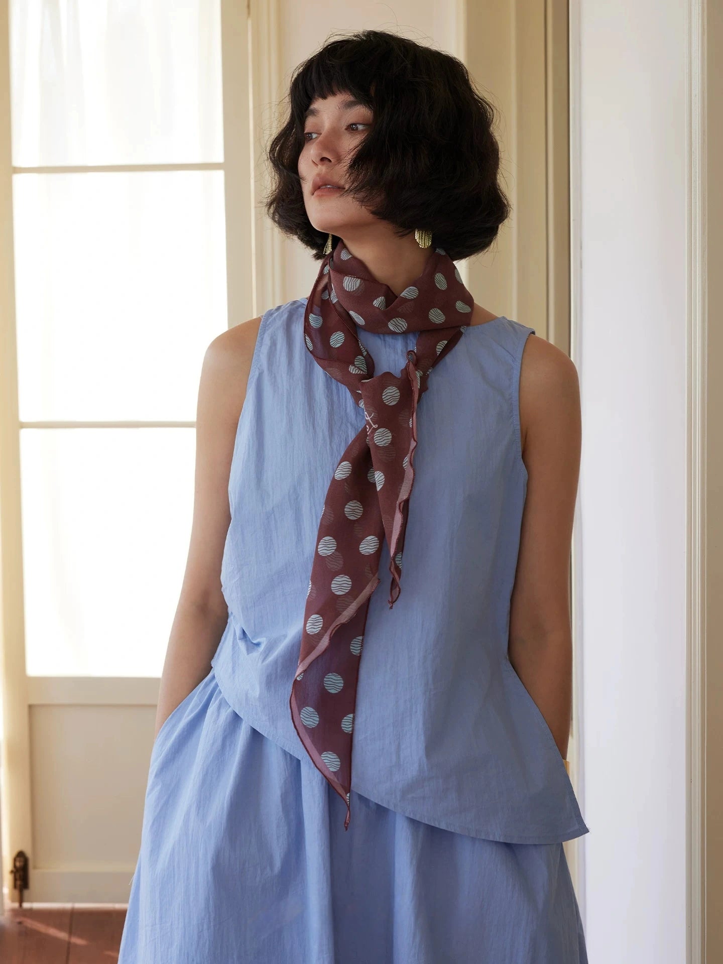 Brown polka dot long silk twilly scarf styled with sleeveless blue dress for classic everyday wear