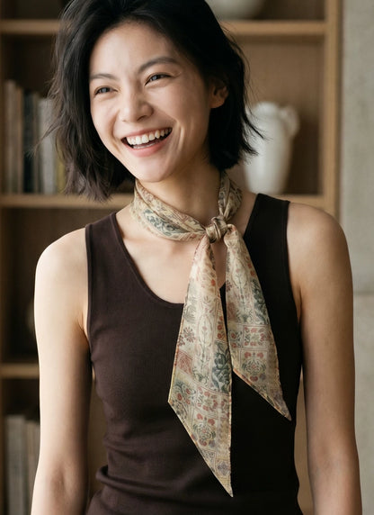 Woman wearing a brown floral mulberry silk skinny scarf tied loosely at the neck with a dark brown top