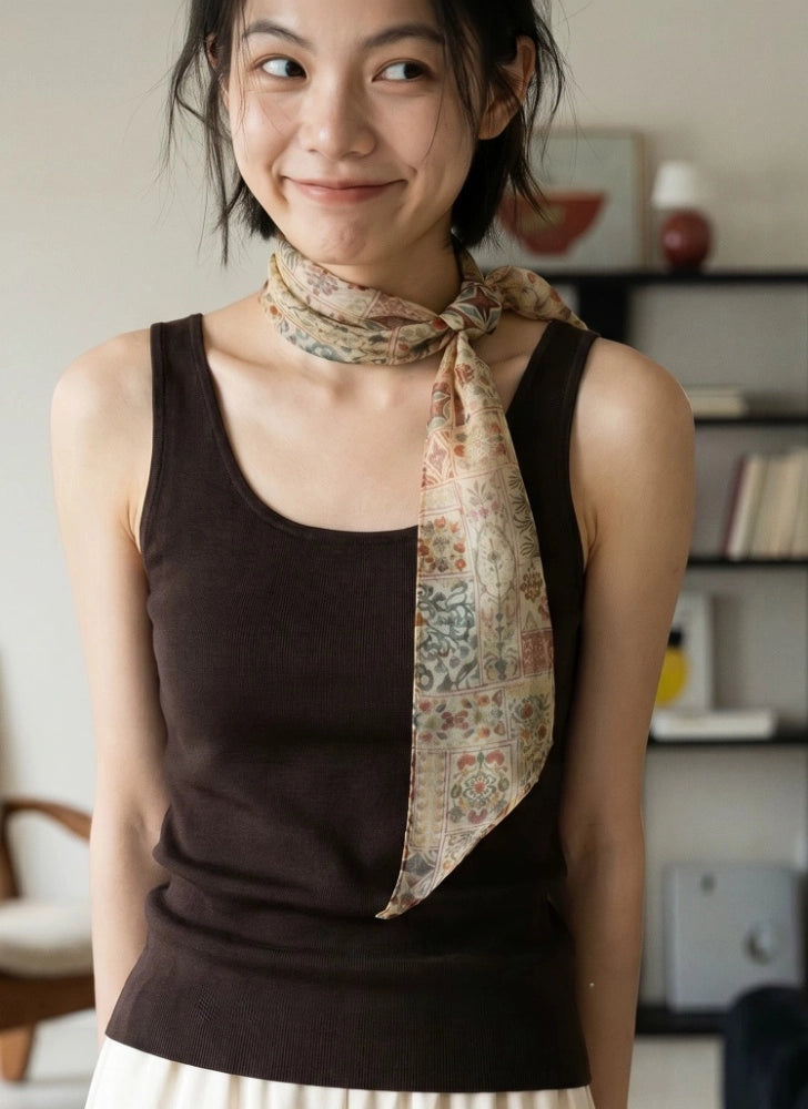 Woman wearing a narrow brown floral silk scarf wrapped at the neck with one long tapered end