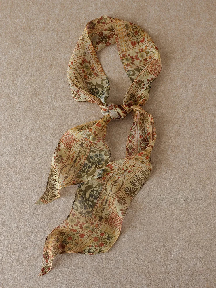 Brown vintage floral mulberry silk skinny scarf arranged in a loose knot on a neutral beige background