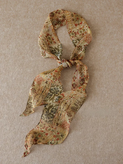 Brown vintage floral mulberry silk skinny scarf arranged in a loose knot on a neutral beige background