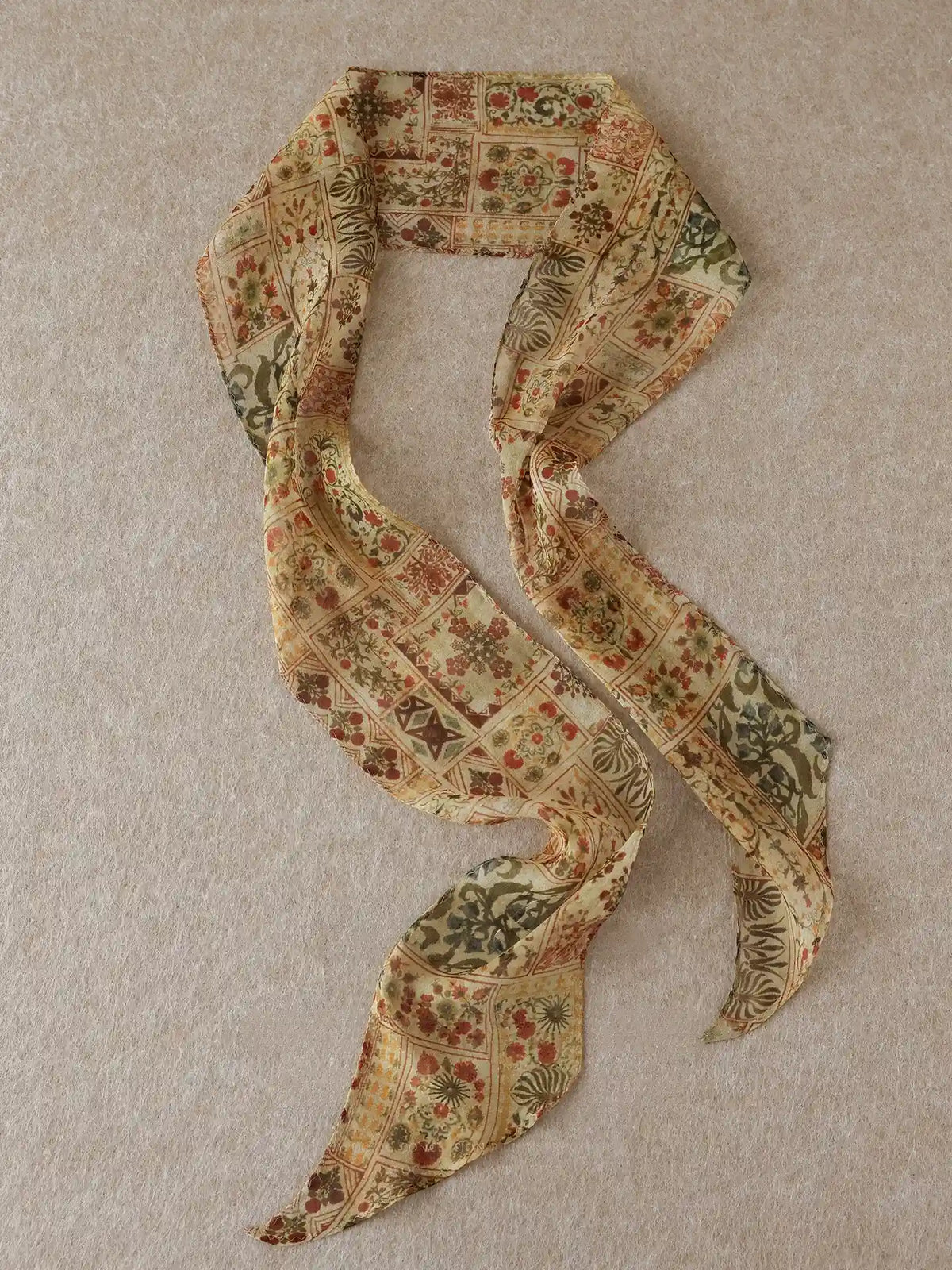 Long brown floral mulberry silk ribbon scarf displayed in a flowing S shape on a neutral beige background