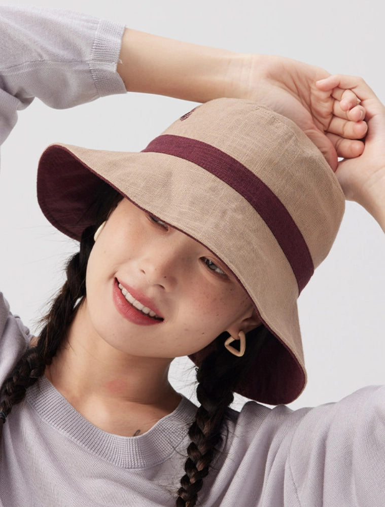 Model wearing the beige side of a reversible bucket hat with burgundy contrast trim