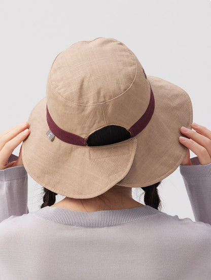 Back view of a beige reversible ramie cotton bucket hat with burgundy trim and adjustable strap