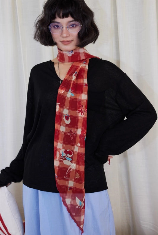 Model wearing a burgundy cherry plaid skinny silk scarf as a long neck scarf with a retro red tartan pattern