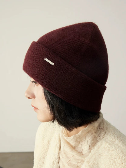 Side-profile model wearing a burgundy 100% cashmere beanie with a cream knit sweater