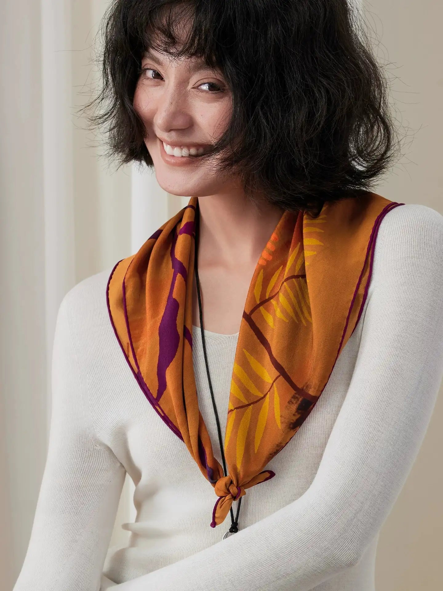 Woman wearing a burnt orange botanical mulberry silk scarf in a relaxed triangular neck drape