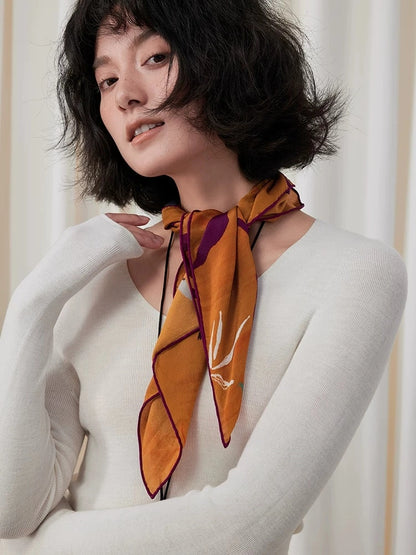 Woman styling a burnt orange silk square scarf as a neat neckerchief with pointed ends