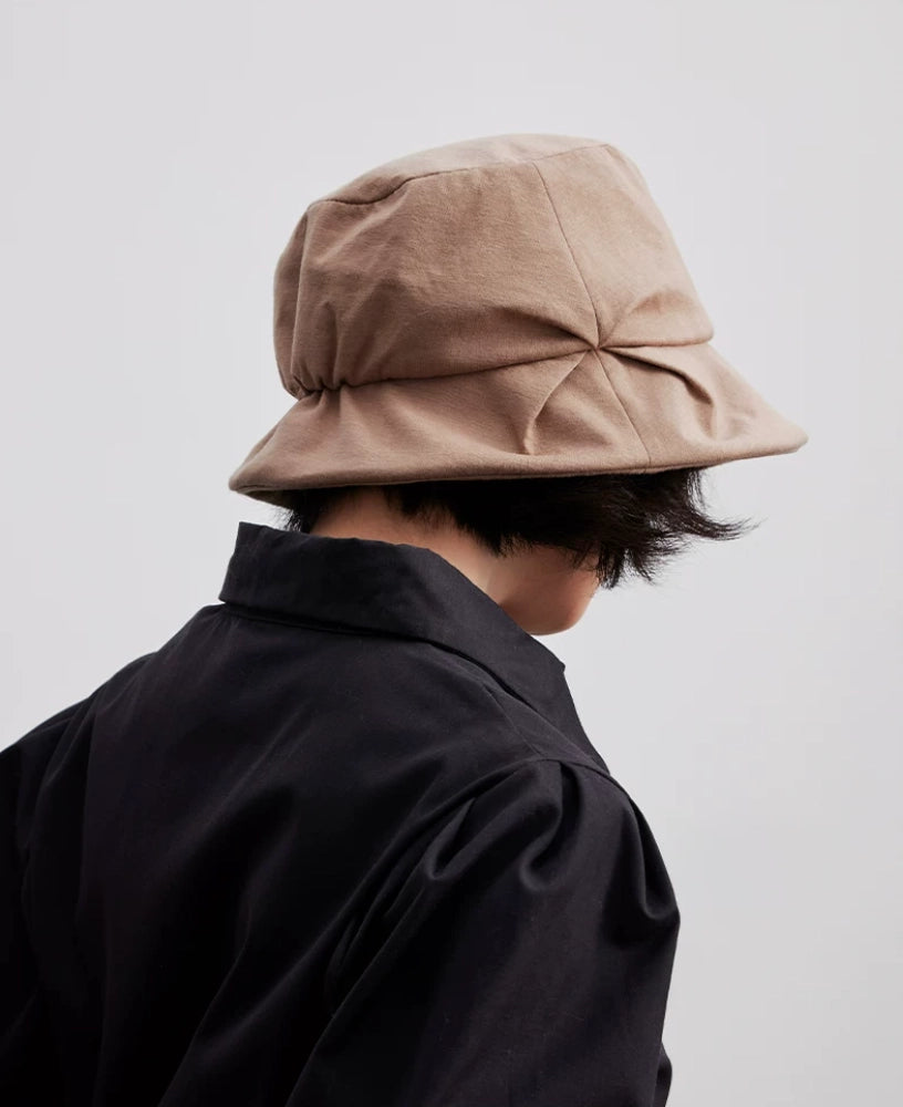 Rear view of a camel pleated bucket hat showing the gathered crown and folded brim
